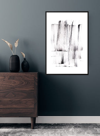 Sort penselstrøg poster with abstract black brush strokes hanging on a dark wall above a wooden dresser.