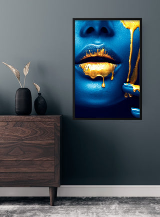 Fashion poster of golden lips on blue skin, with gold paint dripping over mouth, displayed in a modern room.
