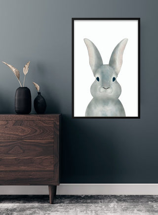 Framed poster with a cute gray bunny illustration, hanging above a wooden dresser in a children’s room.