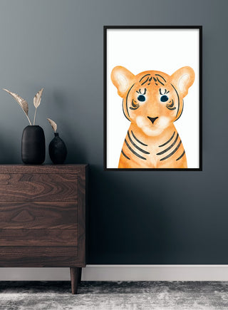 Framed poster of a cute, cartoon tiger with big eyes, hanging on a dark wall in a children's room.