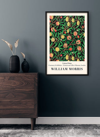 Framed William Morris "Black Lemons" poster with vibrant fruit and floral pattern hanging on a dark wall.
