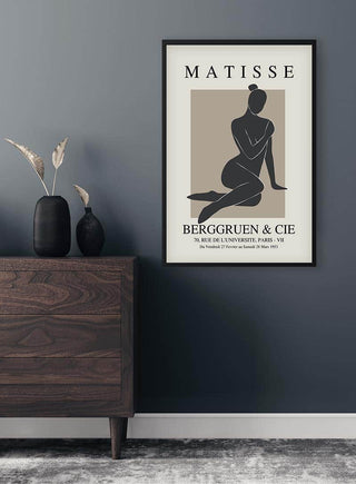 Minimalist poster of a black woman’s silhouette, framed and hung on a modern dark wall above a wooden dresser.