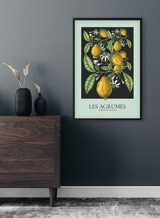 Framed Les Agrumes Green Plakat featuring illustrated lemons and leaves, hanging on a modern gray wall.