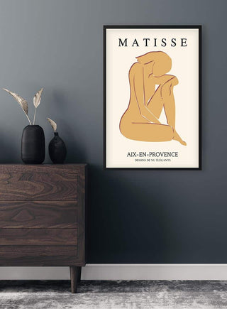 Framed Matisse inspired yellow cutout plakat featuring an abstract seated figure, displayed above a wooden dresser.