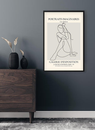 Minimalist line art of a seated woman, displayed in a black frame on a dark wall above a wooden cabinet.