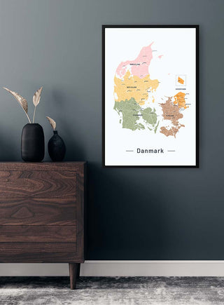 Framed Danmarkskort No 02 Plakat map on a dark wall above a wooden dresser with vases.