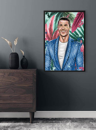 Framed portrait of Christiano Ronaldo by Danii Steinfeldt displayed on a dark gray wall above a wooden dresser.