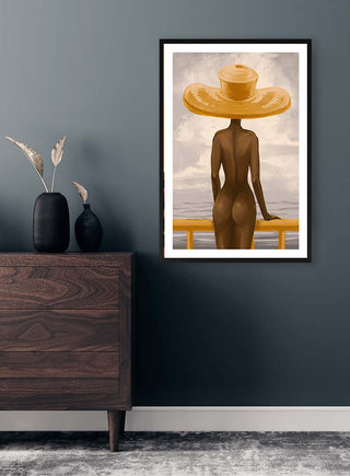 Framed print of a nude figure in a yellow hat, standing by a railing, displayed above a wooden dresser.