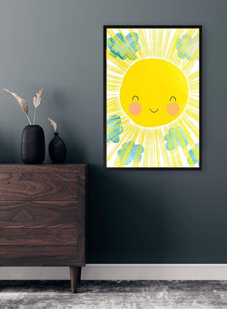 Framed Matahari sun illustration with a smiling face, hanging on a dark wall above a wooden dresser.