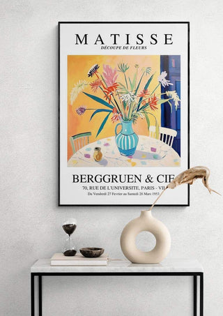 Framed art print of Matisse's vase with flowers displayed above a modern console table with decor.