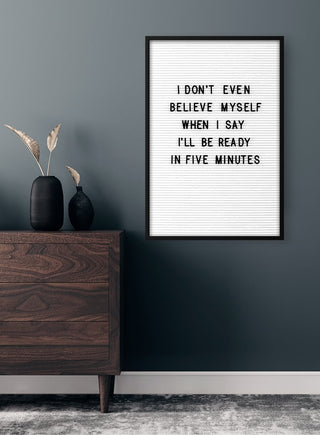 Framed "Don't Believe Myself" poster on a dark wall above a wooden dresser with decorative vases.
