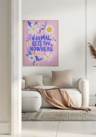 Framed "Normal Gets You Nowhere" floral print hanging above a white sofa in a modern living room.