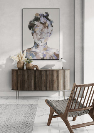 Le Portrait No.III by Gabriella Roberg hangs above a wooden sideboard in a modern, minimalist living room.