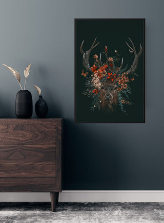 Poster of a deer with antlers adorned with colorful flowers, displayed on a dark wall above a wooden dresser.