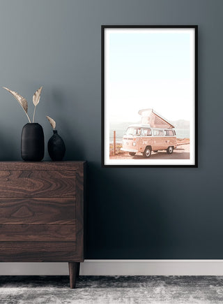 Framed "Pink Van at the Sea" poster displayed on a dark wall above a wooden dresser with vases.