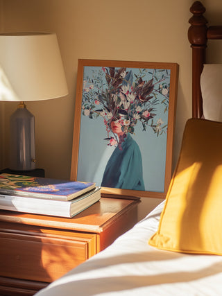 Framed "I Was Hidden but You Saw Me" by Frank Moth on bedside table next to lamp and books.