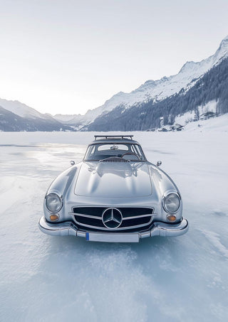 Front view of a retro silver car parked on a frozen lake with snowy mountains in the background.