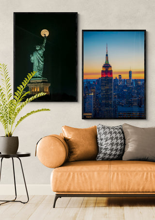 Framed Statue of Liberty artwork by Hua Zhu displayed above a modern tan sofa in a stylish living room.