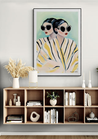 Framed Yellow Twins by David Wolf artwork featuring two women in sunglasses above a modern console shelf.