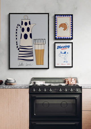 Framed art of a coffee pot, croissant, and "Morning workout" mug displayed above a kitchen stove.